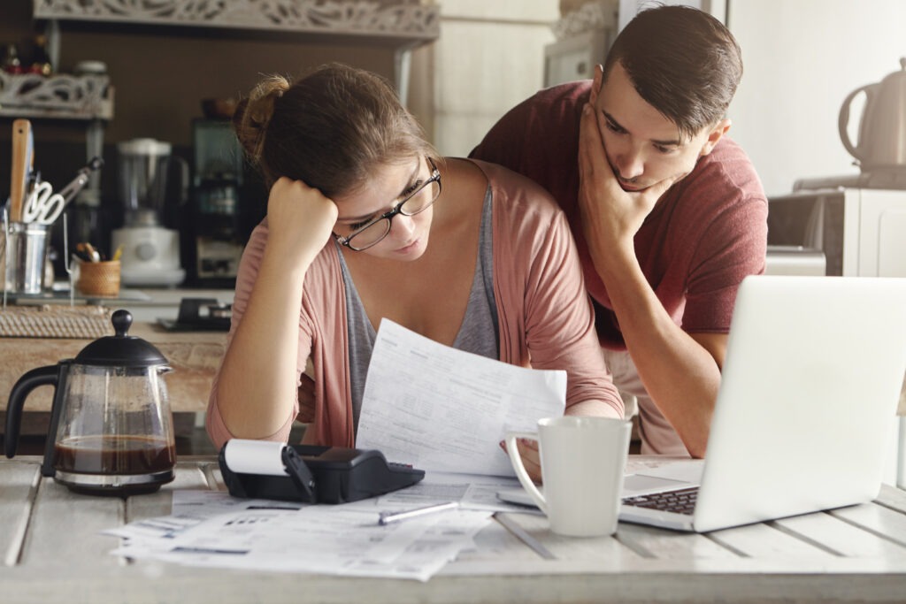 young-stressed-caucasian-couple-facing-financials-troubles-sitting-kitchen-table-with-papers-calculator-laptop-computer-reading-document-from-bank-looking-frustrated-unhappy-1024x683